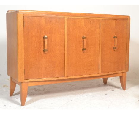 A mid century G-Plan light oak sideboard credenza having and angled, deep and wide body with three cupboard doors having vert