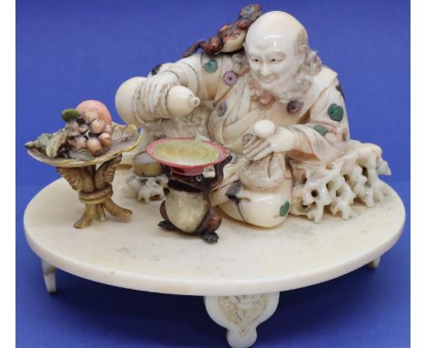 Carved ivory of a seated gentleman with a toad on his head pouring Saki with a fruit table and a toad base table. Chips to ri