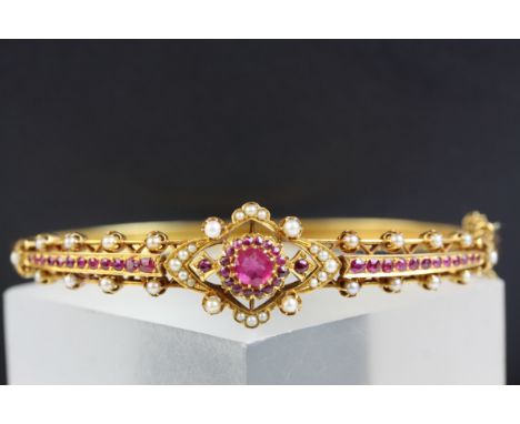 Edwardian style ruby and pearl unmarked yellow gold hinged bangle, the central quatrefoil design and tapered shoulders set wi