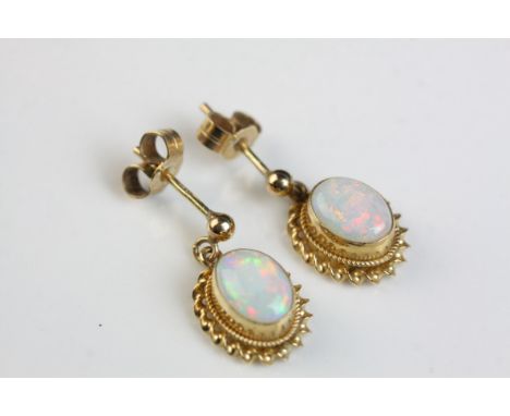 Pair of opal 9ct yellow gold drop earrings, the precious white opal displaying violet, indigo, green, yellow and orange play-