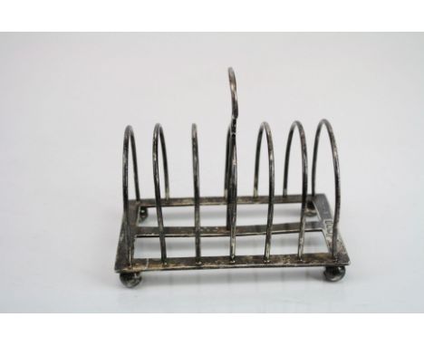 Two similar seven bar silver toast racks raised on four bun feet, makers William Hutton &amp; Sons, Sheffield 1899 and 1921 (