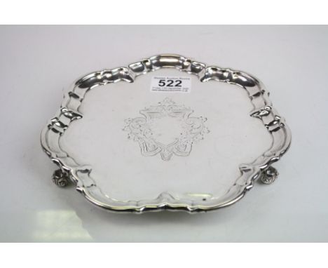Silver card tray raised on three scroll feet, engraved foliate decoration surround blank cartouche to centre, pie crust borde
