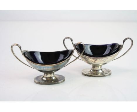 Pair of Victorian silver twin handled pedestal oval salt cellars, plain polished body, reeded foot, blue glass liners, makers