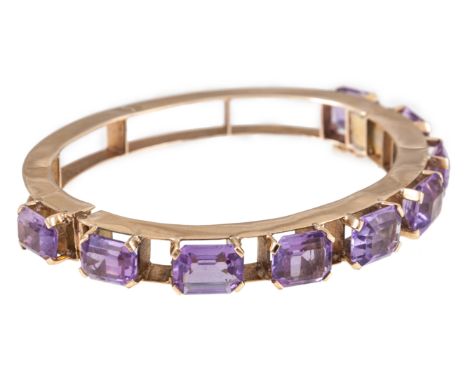 A 9 carat yellow gold and amethyst bangle, nine rectangular step cut amethyst graduating from 11mm x 8mm to 9.5mm x 8.5mm, in