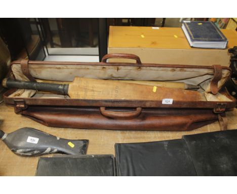 A vintage leather cricket bag containing cricket bat and stumps