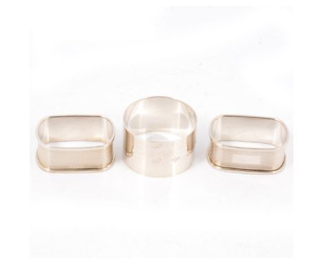 Three silver napkin rings, all by W I Broadway &amp; Co, an oval engine turned pair, Birmingham 1997, 20mm, plain napkin ring