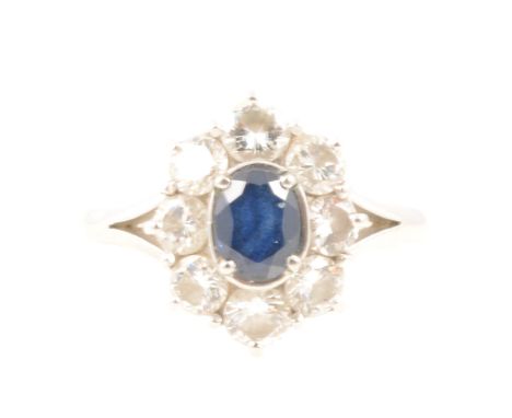 A sapphire and diamond oval cluster ring, the oval mixed cut sapphire 5.5x4.5mm, four claw set and surrounded by eight brilli