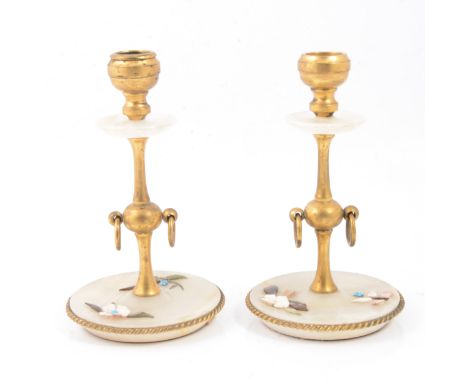 A pair of alabaster candlesticks, applied floral stone decoration to bases, gilded stems, with twin ring handles, sconces and