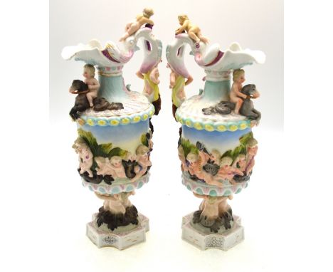 A continental pair of porcelain wine flagons, possibly Sitzendorf, moulded with putti riding dolphins and mythical sea animal