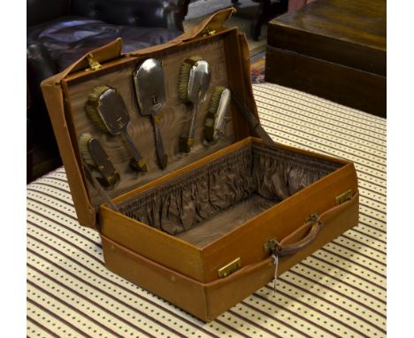 A pigskin travelling-case, the brown watered-silk lining fitted with an Art Deco style six-piece silver brush set with engine