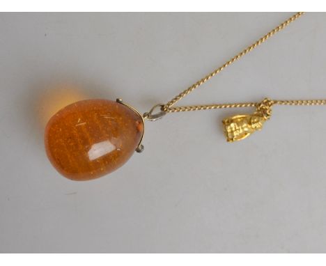 A pear-shaped amber drop suspended from a diamond-set hanger on a yellow metal curb style guard chain stamped 15 to/w seated 