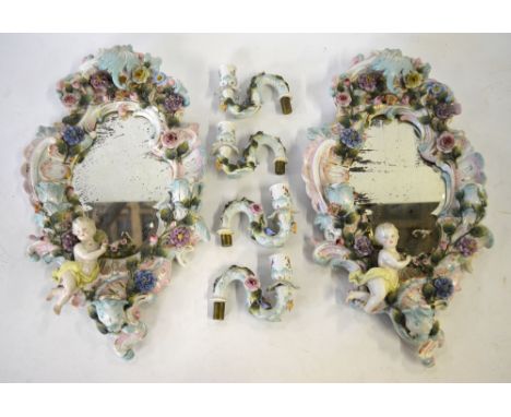 A pair of Sitzendorf oval porcelain girandole mirrors, the scrolling frames decorated in bold relief with roses and other flo