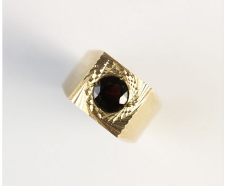 A garnet set 9ct gold ring, Birmingham 1971, the central circular garnet within a square panel, with broad shoulders and tape