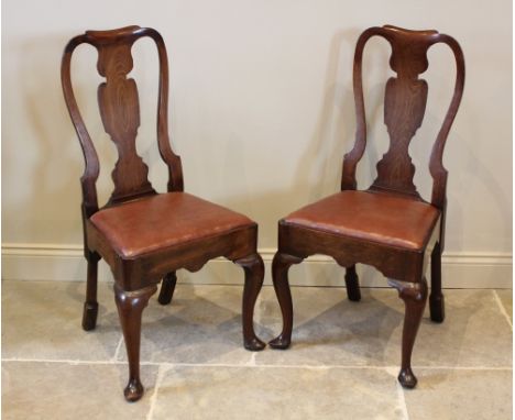 A pair of George I walnut side chairs, each with a vase shaped splat over a drop in upholstered seat and shaped apron, raised