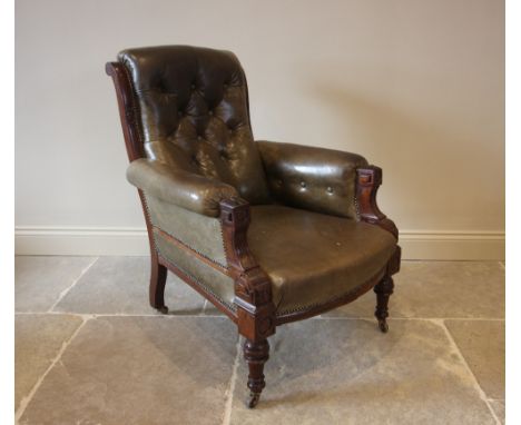 A late Victorian green leather and walnut drawing room chair, the button back over padded arms extending to carved aesthetic 