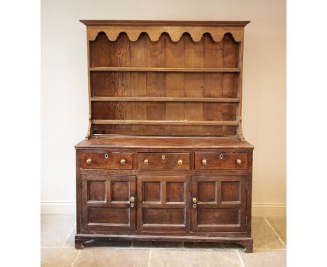 A George III oak dresser, the later associated plate rack with a scalloped frieze and three shelves, upon the base with a rec