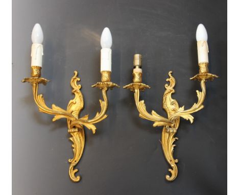 A pair of French ormolu Rococo style twin branch wall light fittings, cast as intertwined foliate branches against a 'C' scro