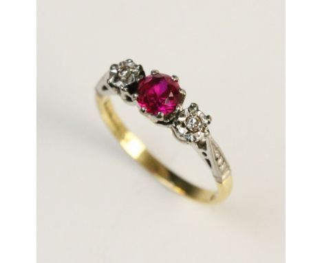 A synthetic ruby and diamond three stone ring, comprising a central round mixed cut untested (suspected synthetic) ruby measu