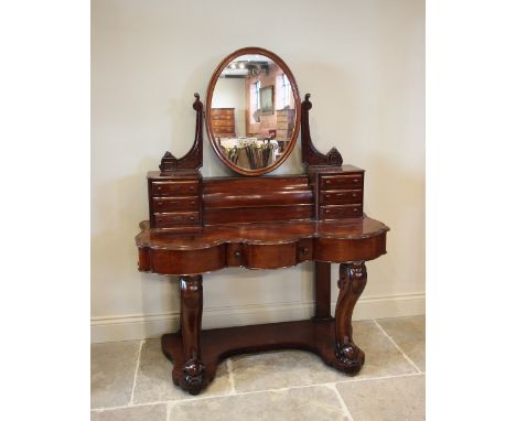 A Victorian mahogany Duchess dressing table, the tilting oval mirror above a fall front cylindrical compartment, flanked by t