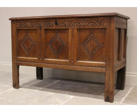 A late 17th/early 18th century oak coffer, with a carved frieze over three panels incised with a lozenge design raised upon s