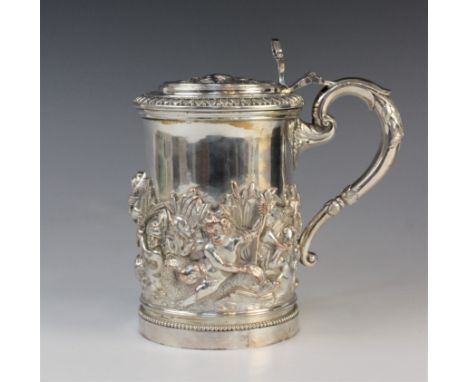 A large 19th century silver plated tankard, of cylindrical form with hinged cover and cast scrolling handle, elaborately embo