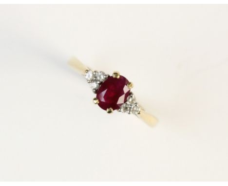 A ruby and diamond 9ct gold ring, the central oval mixed cut ruby measuring 7mm x 5mm, with three round brilliant cut diamond