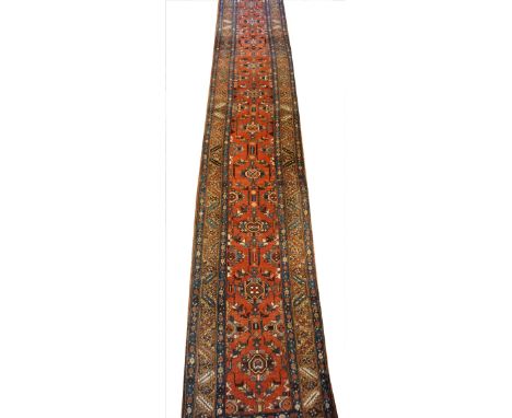 A large Turkish geometric runner, with a traditional repetitive medallion design against a predominantly red ground within a 