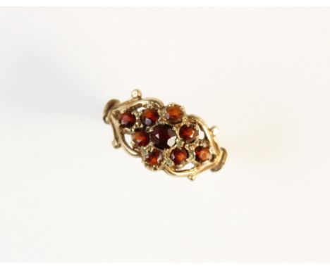 A garnet set 9ct gold ring, the central tiered floral cluster comprising a central round mixed cut garnet measuring 3.5mm dia