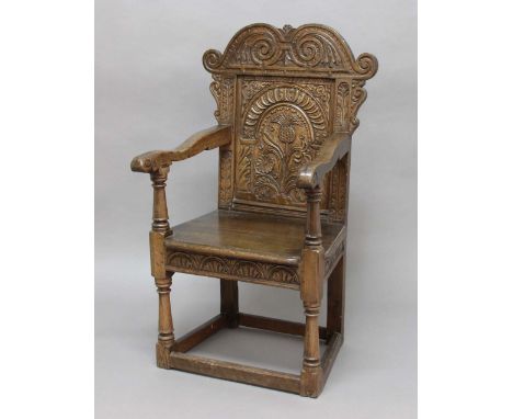 ENGLISH JOINED OAK WAINSCOT OR ARM CHAIR, mid 17th century, the foliate scrolling crest rail above a single panel back carved