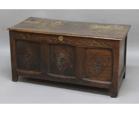 OAK COFFER,  early 18th century, the hinged cover enclosing a vacant interior above a triple panel front with lozenge carving