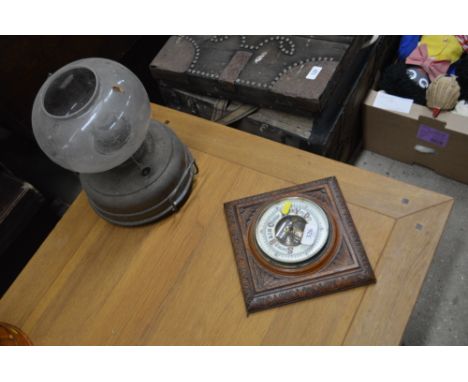 An early 20th Century carved oak framed barometer and an oil lamp