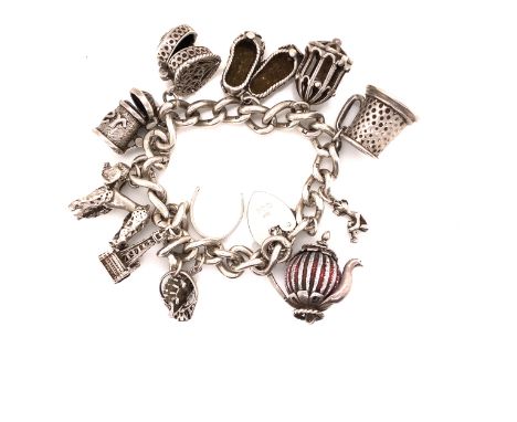 A HALLMARKED SILVER VINTAGE CHARM BRACELET, COMPLETE WITH AN ASSORTMENT OF SILVER CHARMS, AN ATTACHED SAFETY CHAIN AND PADLOC