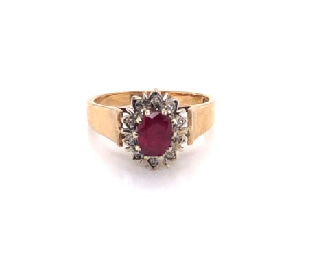 A 9ct HALLMARKED GOLD RUBY AND DIAMOND CLUSTER RING. THE CENTRAL OVAL CUT RUBY IN A TEN CLAW RAISED SETTING FRAMED BY A CLUST