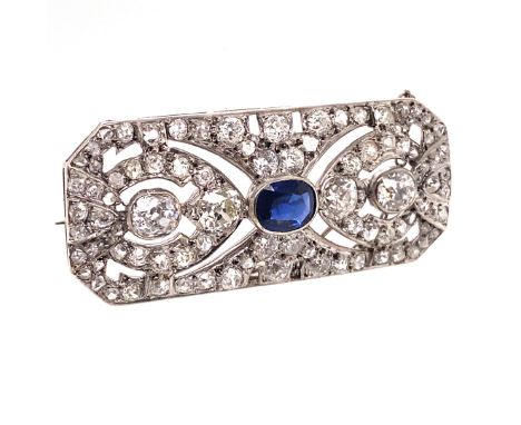 AN EDWARDIAN SAPPHIRE AND DIAMOND PANEL BROOCH. THE CENTRE OVAL MIXED CUT SAPPHIRE A MEDIUM TO DARK BLUE, CALCULATED WEIGHT 1
