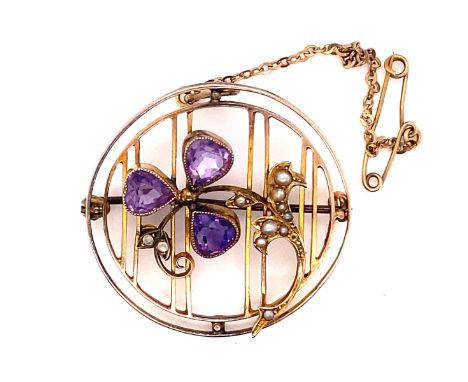 AN EDWARDIAN AMETHYST AND SEED PEARL OPENWORK BROOCH WITH ATTACHED SAFETY CHAIN. THE THREE PEAR CUT AMETHYST FORMING A CLOVER