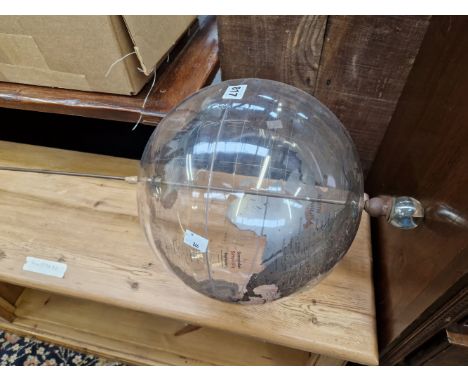 A CLEAR PLASTIC TERRESTIAL GLOBE ROTATING ON AN IRON ROD