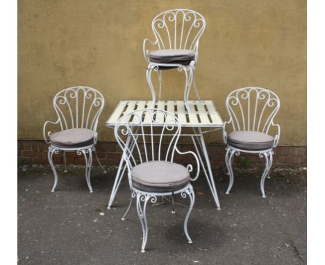 An early 20th century white painted wrought iron patio suite comprising of four scroll spoon back armchairs and a table with 