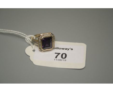 An amethyst and diamond cluster ring, the rectangular step cut amethyst with a diamond set border in 9ct gold mount