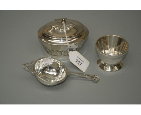 A small silver tea caddy of oval shape, the hinged lid with urn finial over lobed body, London 1912, together with a tea stra