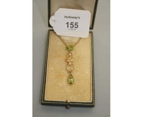 An Edwardian peridot and seed pearl negligee pendant with cushion cut peridot suspending a seed pearl scroll-ware frame and p