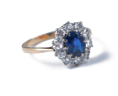 A sapphire and diamond cluster ring, the oval cut sapphire claw mounted above a border of brilliant cut diamonds to plain sha