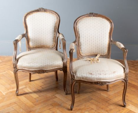 A pair of 19th century French beech and pine open armchairs, each with leaf carved rail, spoon back, fluted arms, serpentine 