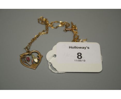 An Art Nouveau ruby and enamel foliate heart-shaped open work pendant to a 9ct gold trace link chain, chips to the enamel