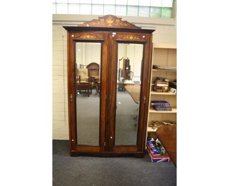 An Edwardian rosewood, marquetry inlaid and strung double wardrobe, the shaped pediment with urn and swag detail over a pair 