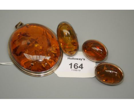 A modern suite of amber jewellery comprising a large oval pendant, a ring and a pair of pendant earrings. The white metal mou