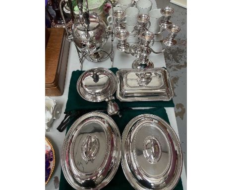 Group of silver plate to include a spirit kettle on stand, pair of three branch candelabrum, pair of oval tureens with covers