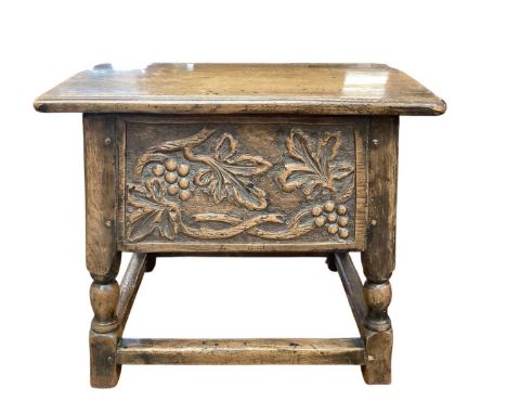 Carved oak stool with hinged lid, leaf and berry decoration on turned and block supports joined by stretchers, 56cm wide, 41c