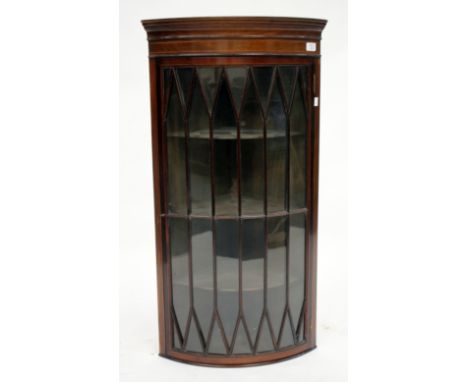 AN EDWARDIAN MAHOGANY AND STRING INLAID HANGING CORNER CABINET of bow fronted form, the astragal glazed door enclosed three s