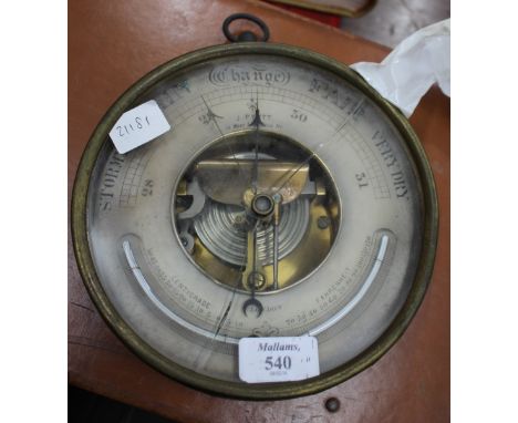A 19TH CENTURY BRASS AND IRON ANEROID BAROMETER by J. Pyott, West India Dock Road, 20cm diameter 
