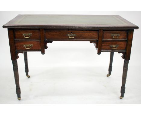 A LATE 19TH CENTURY MAHOGANY DESK with a green leather inset top and five drawers with turned tapering legs and ceramic casto